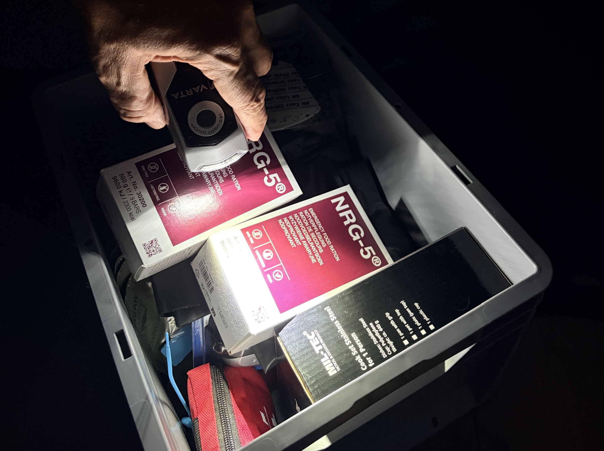 Eine Hand nimmt eine Kurbellampe aus einem geöffneten Karton